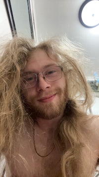 a man with long hair and glasses is taking a selfie